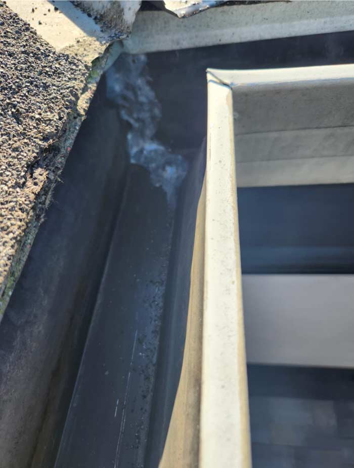 Interior view of a newly installed, seamless aluminum gutter by Quality Roofing Services, Inc., showcasing the clean craftsmanship and watertight seals of a professional installation.