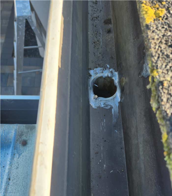 Detailed view of a gutter downspout opening during a maintenance service, showing professional sealing and repair work to prevent leaks in a Contra Costa County home.